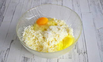 Сыр для начинки натрите на крупной терке. Смешайте его с двумя яйцами, немного посолите.