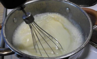 Снова ставим посуду с молоком на плиту. Как только появятся первые пузырьки, вливаем тонкой струей яично-молочную смесь. Сразу же взбиваем до густоты. Убираем массу с плиты и даем ей немного остыть.