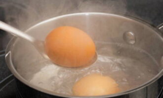 Отварите яйца вкрутую. Для этого поставьте кастрюльку с водой и яйцами на огонь и варите 8-10 минут после закипания. Чтобы они легче чистились, посолите воду в начале готовки. По готовности переложите яйца в очень холодную воду и дождитесь остывания. Очистите их от скорлупы и измельчите в крошку.