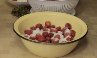 Только после этого удаляйте чашелистики ягод, иначе при мытье клубника без них быстро потеряет свой вид и раскиснет. Их можно удалять вилкой или специальным ножом. Затем кладите ягоды в посуду, в которой будете готовить. Уже подготовленные ягоды засыпайте 150-200 гр. сахара.