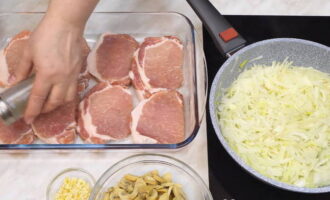 Приступайте к обжариванию лука. Налейте в сковородку растительное масло и обжарьте лук. В это время уложите мясо на противень или в форму. Поперчите и посолите мясо по вкусу.