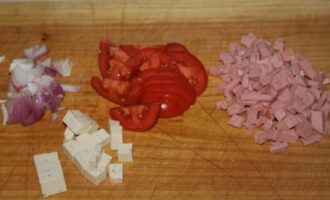 Нарезаем колбасу и сыр кубиками, помидор – дольками, шинкуем красный лук.