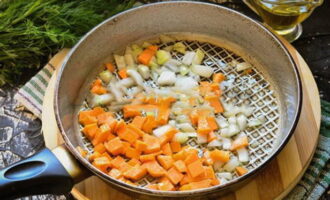 Тем временем покрошите очищенные лук и морковь. На сковороде разогрейте растительное масло и обжарьте на нем овощи до мягкости, постоянно помешивая, чтобы ничего не пригорело.