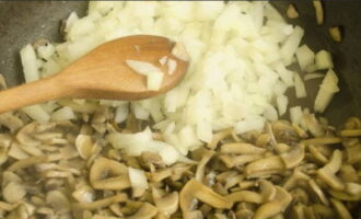 В грибы добавляем измельченный лук и продолжаем обжаривать лук до появления легкого румянца.