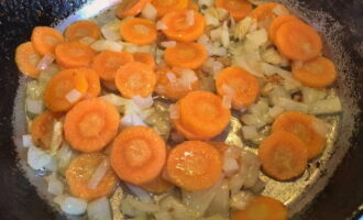 Тонким кружочками режем очищенную морковь. Обжариваем продукт с оставшимся репчатым луком до мягкого состояния.