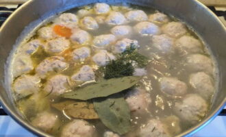 Выкладываем в суп измельченную зелень и лавровые листочки. Варим блюдо на слабом огне еще 15 минут.