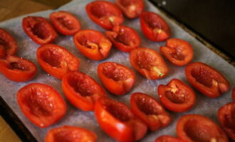 На противне разложить половинки томатов срезом вверх плотно друг к другу. Присыпать овощи солью, сахаром, гранулированным чесноком и свежемолотым перцем.