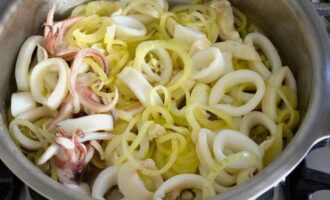 Когда овощи немного подрумянятся, добавить к ним мясо кальмара и готовить несколько минут. 