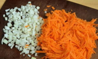 Подготовим лук и морковь для зажарки. Очищаем лук от шелухи, разрезаем его на две части. Каждую часть измельчаем на небольшие кубики. Морковь также очищаем и промываем теплой водой от грязи. Натираем ее на крупной терке в глубокую миску.