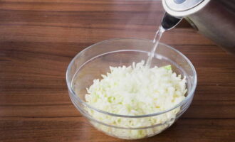 Измельченную капусту с луком перекладываем в миску и заливаем только что закипевшей водой, после чего оставляем настаиваться в течение 10 минут. Спустя это время откидываем овощи на дуршлаг, чтобы вся вода стекла.