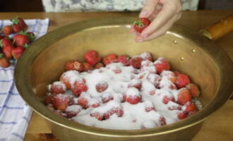 Оборвав чашелистики, переложите ягоды в небольшой металлический тазик или кастрюлю и засыпьте равномерным слоем сахара. Можете засыпать ингредиенты послойно, так сок из ягод будет выделяться активнее. Затем слегка потрясите тару, чтобы сахар просыпался между плодов.