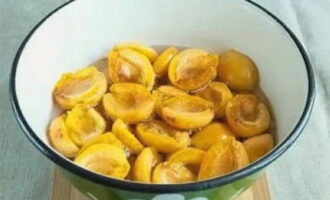 Подготовленные абрикосы сложите в другую, чистую кастрюлю. Залейте плоды горячим сахарным сиропом так, чтобы он равномерно покрывал их. Оставьте фрукты настаиваться, пока жидкость не остынет полностью. За это время абрикосы пустят сок и впитают часть сладости.