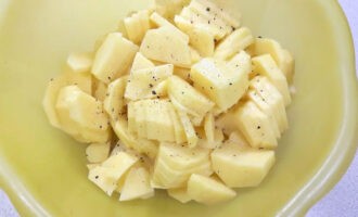 Нарезанный картофель поперчите и посолите. Можете также добавить к нему немного растительного масла и перемешать, так картофель не будет темнеть и получится более поджаристым.