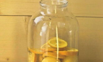 В 3-литровую банку, которую нужно сначала простерилизовать, кладем абрикосы и ломтики апельсина, затем заливаем фрукты кипятком. 