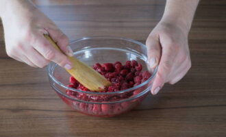 Высыпать малину в подходящую по объему миску и слегка размять, чтобы ягоды пустили сок, но не превращать в пюре. 
