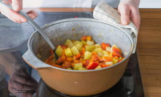 Далее добавьте картофель и морковь, продолжайте жарить 10 минут. После этого выложите перец и помидоры, перемешайте и готовьте еще 5 минут.