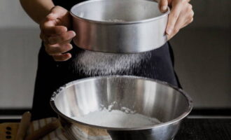 Как испечь песочный пирог с вишней в духовке? Просеять муку в глубокую емкость для замешивания теста и смешать ее с сахарной пудрой. 