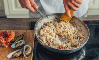 Из заготовки на время убираем морепродукты. Рис со специями старательно вымешиваем. Раскладываем ризотто по тарелкам, дополняем морепродуктами и подаем к столу.