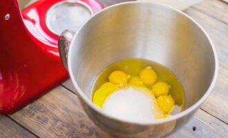 Яйца разбейте в чашу миксера, добавьте сахар и взбейте ингредиенты. Масса должна увеличится в три раза и стать светлой.