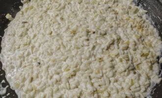 После этого добавьте сливки, лук и соль, перемешайте и продолжайте тушить рис до легкой твердыни внутри.