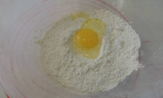 Как приготовить классические равиоли в домашних условиях? В глубокую посуду просеиваем муку со щепоткой соли. Сюда же разбиваем куриное яйцо и вливаем ложку масла.