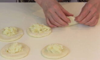 В центр каждой лепешки выкладываем приготовленную ранее начинку, используя десертную ложку. Так вам будет проще ориентироваться по объему. И защипываем лепешку по краям, формируя из нее пирожок.