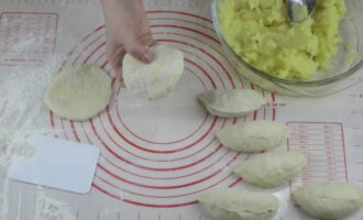 Делим подошедшее тесто на одинаковые кусочки и скатываем их в шарики, которые после разминаем в лепешки. Раскладываем в середину каждой начинку и соединяем края.