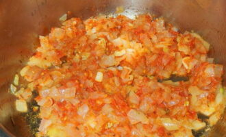 Проверяем состояние лука и заправляем его томатной пастой и зирой. Обжариваем содержимое еще на протяжении минуты. Параллельно с этим натираем морковь на крупной терке.