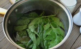 Молодую крапиву выкладываем в миску. Промываем ее и отрываем от стебля листочки. Добавляем листья в суп, перемешиваем его и накрываем крышкой. Варим 10 минут.
