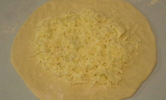 В центр заготовки выкладываем не меньше 200 грамм измельченного сыра.