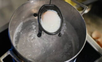 В сотейнике закипятить воду и поставить его на слабый огонь. Аккуратно вылить разбитое яйцо в воду и готовить 60 секунд. Затем достать его шумовкой из кипятка и выложить на салфетку. При необходимости довести яйцо пашот до полной готовности, подержав его в горячей воде не более 10 минут. Повторить процедуру со вторым яйцом. 