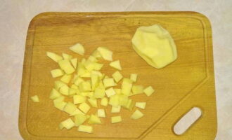 В это время очищаем картофель, промываем его и нарезаем кубиками среднего размера. Берём трёхлитровую кастрюлю, наливаем в неё воду и ставим на огонь. Забрасываем туда нарезанную картошку, добавляем немного соли и оставляем вариться.