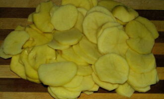 Тонкими кружками нарежьте очищенный и промытый картофель.