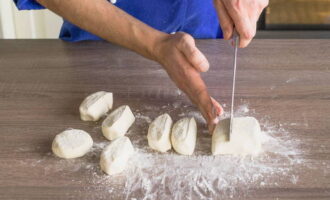 Из получившегося теста скатать колбаску, разделить на порционные кусочки и сформировать сырники, слегка присыпая их мукой, чтобы не липли к рукам. 