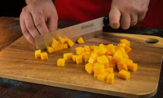 С оранжевого овоща снимаем плотную кожуру, извлекаем часть с семенами и нарезаем мелкими кубиками.