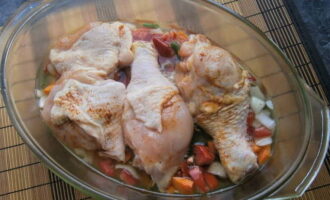 Далее посыпаем курицу приправой для курицы и выкладываем её на овощи. Затем заливаем всё водой комнатной температуры так, чтобы она покрывала овощи с рисом.