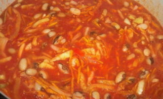 Когда фасоль будет готова, сливаем воду. Вливаем в кастрюлю томатный сок. Следом отправляем нарезанные лук, перец и морковь. Добавляем растительное масло, соль и сахар. Ждем, пока масса закипит. Продолжаем варить фасоль с овощами около получаса, не забывая постоянно помешивать блюдо.