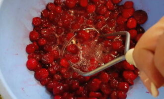 Затем размороженную ягоду с помощью картофельной толкушки максимально раздавите, чтобы ягода дала немного сока. Дело это нелегкое, так как клюква достаточно упруга.