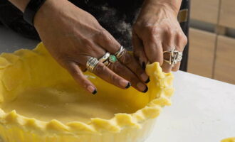 Обрезаем лишнее тесто ножом и красиво защипываем края заготовки. Прокалываем тесто вилкой.