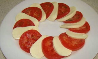 Теперь берём подходящую круглую тарелку и выкладываем на неё нарезанную моцареллу с помидором, чередуя их между собой.
