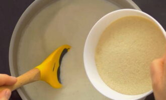 Творожный пудинг приготовить очень легко. В кастрюлю влейте молоко, поставьте его на медленный огонь, нагрейте. Затем добавьте соль и манную крупу.