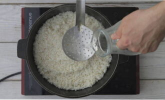 Через час уложите ровным слоем поверх зирвака промытый рис. Затем огонь увеличьте до максимального и через шумовку или по стенке казана налейте кипяток. Уровень воды должен быть на 3 см выше слоя риса.