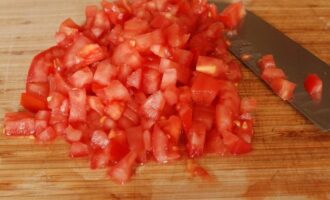 Промываем помидоры и избавляемся от шкурки: делаем надрезы на макушках томатов в виде креста и ошпариваем помидоры кипятком, через пару минут шкурка легко «слезет» с мякоти плодов. Нарезаем помидоры кубиками (семечки удаляем). 
