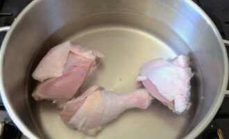 Курицу разрезаем на несколько крупных кусков, после чего хорошо промываем её под проточной водой, перекладываем в кастрюлю и заливаем водой. Отправляем всё на огонь, доводим до кипения, добавляем соль по вкусу и варим в течение 30 минут.