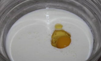 Теперь займемся тестом. В миску с глубоким дном наливаем кефир (можно заменить ингредиент молоком или простоквашей). Вбиваем к кефиру одно яйцо. Подсаливаем массу по вкусу и слегка взбиваем вилкой до соединения продуктов.