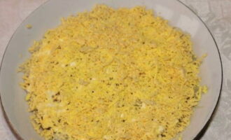 Отвариваем куриные яйца, очищаем их и делим на белки и желтки. Желтки измельчаем и укладываем вторым слоем.
