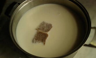 Вливаем молоко в кастрюлю и нагреваем его до теплого состояния. Для закваски опускаем сюда пару небольших кусочков черного хлеба.