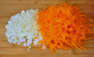 Срезаем грязный слой моркови, вымываем ее водой. Натираем морковь на терке со стороны крупных отверстий. Очищенную луковицу также мелко нарезаем. 