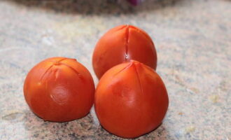 Необходимое количество томатов – 3 штуки – нужно избавить от кожицы. Для этого надрезаем верхушку каждого помидора (надрез должен быть в форме креста) и выкладываем их в глубокую емкость. Заливаем воду в чайник или кастрюлю и доводим до кипения. Затем заливаем кипятком помидоры. Через 2 минуты меняем горячую воду на холодную. Теперь кожицу можно легко снять. Нарезаем томатную мякоть кубиками.