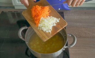 Одну морковь очищаем, промываем и натираем на крупной тёрке. Репчатый лук также очищаем и мелко нарезаем ножом. Отправляем подготовленные овощи в кастрюлю к картофелю с горохом, после чего добавляем соль с чёрным молотым перцем по вкусу.